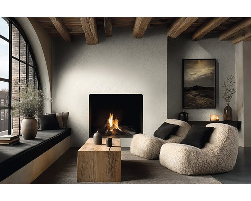 Salon moderne avec cheminée, murs texturés et poutres en bois. Fauteuils, une table en bois et un coin fenêtre confortable.
