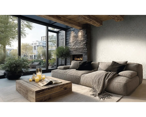 Salon lumineux avec canapé gris, table basse en bois rustique, cheminée en pierre et grandes fenêtres. Papier peint discret et poutres apparentes.