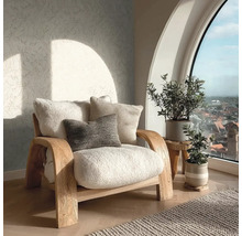 Helles Wohnzimmer mit einem hölzernen Sessel mit weichen Polstern, gemusterter Tapete und Zimmerpflanzen vor einem großen Bogenfenster.
