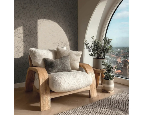 Heller Sessel mit Kissen neben Zimmerpflanzen und einem Fenster