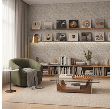 Pièce meublée de façon moderne avec fauteuil vert, table basse en verre et étagères en bois sur papier peint gris texturé.