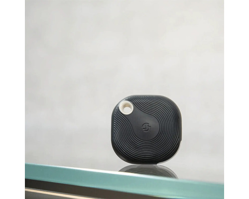 Traceur Bluetooth noir avec motif ondulé et ouverture ronde pour la fixation.