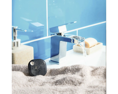 Détecteur de fuite d eau noir sur une serviette grise devant un robinet de lavabo dans une salle de bains lumineuse.