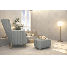 Salon avec fauteuil, tabouret, lampadaire et un chat dormant sur le tabouret