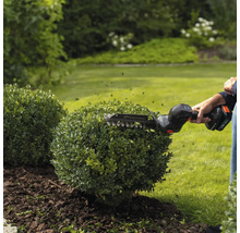 Taille-haie sans fil Husqvarna en cours d'utilisation pour tailler un buisson