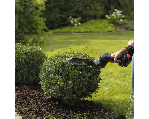 Taille-haie sans fil Husqvarna en cours d'utilisation pour tailler un buisson