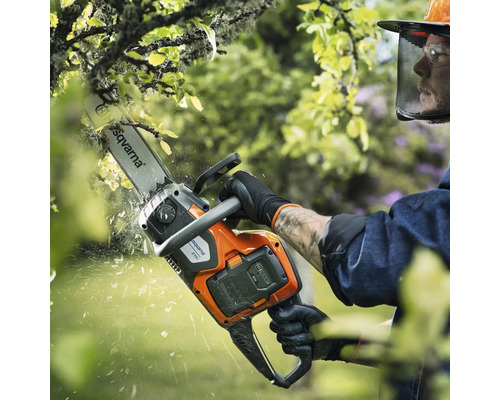 Une personne utilise une tronçonneuse à batterie Husqvarna pour élaguer un arbre.