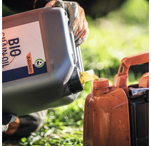 Une personne verse de l'huile de chaîne biologique dans un récipient.