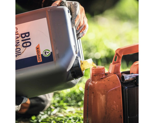 Une personne verse de l'huile de chaîne biologique dans un récipient.