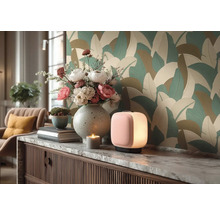 Modernes Zimmer mit großflächiger Blatttapete. Auf einem Sideboard mit Marmorplatte stehen eine Tischlampe, eine Vase mit Blumen und Dekoration.