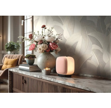 Helle Vliestapete mit Blattmuster im Wohnzimmer hinter einem Sideboard mit Blumenvase und kleiner Lampe.