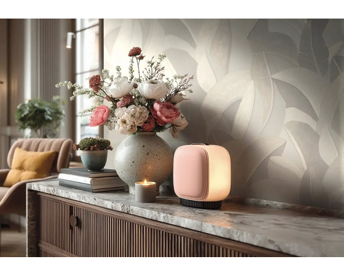 Helle Vliestapete mit Blattmuster im Wohnzimmer hinter einem Sideboard mit Blumenvase und kleiner Lampe.