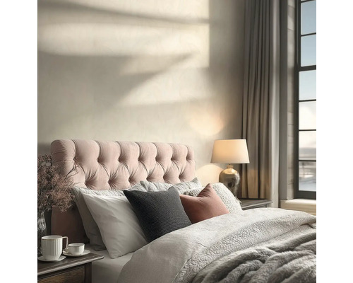 Helles Schlafzimmer mit gestepptem Kopfteil, strukturiertem Bettzeug, einer Tischleuchte und Sonnenlichtschatten auf der Wand.