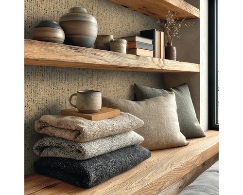 Étagère en bois rustique et mur avec papier peint texturé, vases, coussins et couvertures empilées dans un salon confortable.