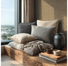 Banquette de fenêtre en bois avec coussins décoratifs, couverture texturée, vase sombre et papier peint texturé.