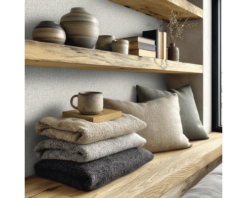 Strukturierte Wandbekleidung in einem hellen Raum mit Holzregalen, Keramik, gefalteten Decken und Kissen im modernen Naturstil.