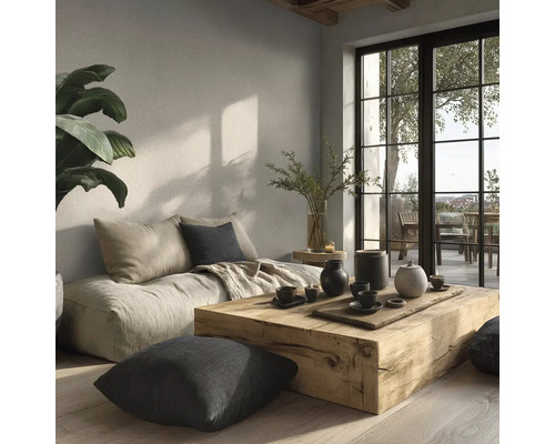 Helles Wohnzimmer mit massivem Holztisch, bodentiefem Sofa, Kissen und großen Fenstern im minimalistischen Stil mit natürlicher Wandgestaltung.