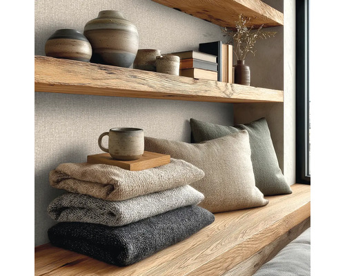 Wandgestaltung mit strukturierter Vliestapete in Leinenoptik, kombiniert mit massiven Holzregalen, Keramik und weichen Strickdecken.