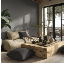 Salon lumineux avec coussins d'assise, table en bois et décoration devant un mur structuré