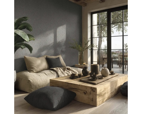 Salon lumineux avec coussins d'assise, table en bois et décoration devant un mur structuré