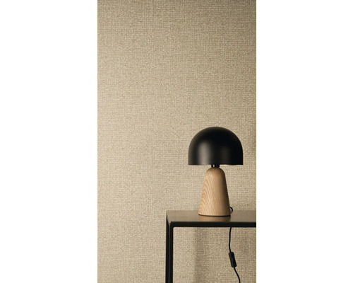 Papier peint intissé avec structure en lin et aspect tissé, au premier plan une lampe de table moderne avec abat-jour noir et pied en bois.