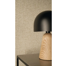 Lampe de table moderne avec un abat-jour en forme de dôme noir et un socle en bois devant un papier peint texturé à l'aspect tissé.
