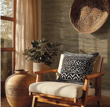 Salon avec fauteuil en bois, coussin à motifs, plante en pot, vase décorative et panier mural