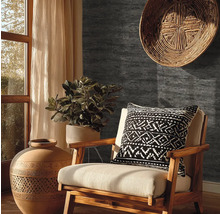 Papier peint gris foncé aspect pierre dans un salon rustique avec fauteuil en bois, vase en terre cuite et plante verte.
