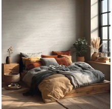 Helles Schlafzimmer mit Bett auf Holzpodest, vielen Kissen und Zimmerpflanzen.