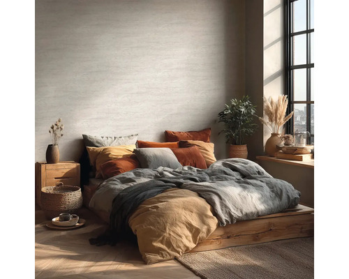 Helles Schlafzimmer mit Bett auf Holzpodest, vielen Kissen und Zimmerpflanzen.