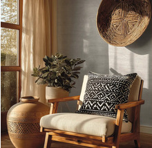 Dekoratives Interieur mit einem Stuhl, einem Kissen mit geometrischem Muster, einer großen Vase und einer Zimmerpflanze.