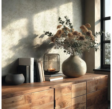 Holzkommode mit Keramikvase, Trockenblumen, Glaswindlicht mit brennender Kerze, Büchern und Dekoschale vor einer hell gemusterten Tapete.
