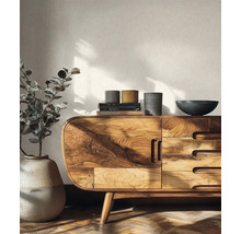 Helles Wohnzimmer mit einem modernen Sideboard aus Holz mit abgerundeten Ecken und markanter Maserung vor einer strukturierten Tapete.