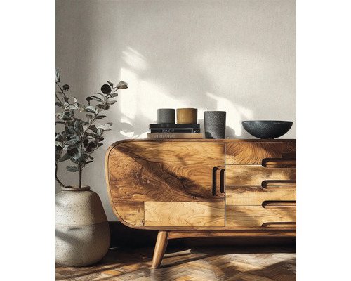 Helles Wohnzimmer mit einem Sideboard aus Massivholz, einer großen Bodenvase mit Pflanze und strukturierter Tapete.