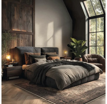 Modern rustikales Schlafzimmer mit Polsterbett, Holzwandverkleidung, Ledersessel, großer Grünpflanze und Fischgrätparkett.
