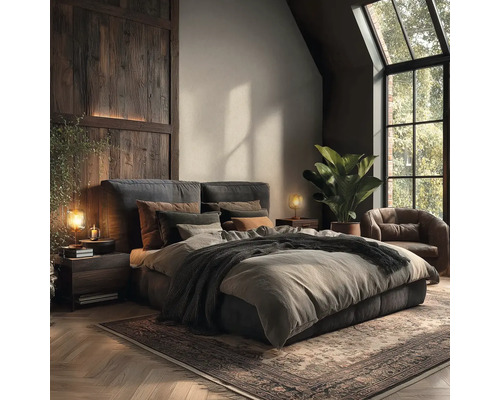 Modern rustikales Schlafzimmer mit Polsterbett, Holzwandverkleidung, Ledersessel, großer Grünpflanze und Fischgrätparkett.