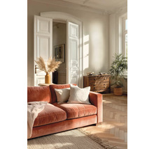 Helles, geräumiges Wohnzimmer mit terracottafarbenem Samtsofa, Fischgrätparkett, Holzkommode und Zimmerpflanzen im klassischen Stil.