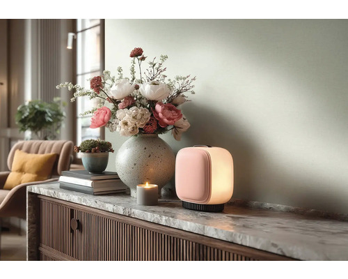 Moderne tragbare Tischleuchte mit rosa Front und weißem Licht auf einem Sideboard mit Marmorplatte neben einer Blumenvase und einer Kerze.