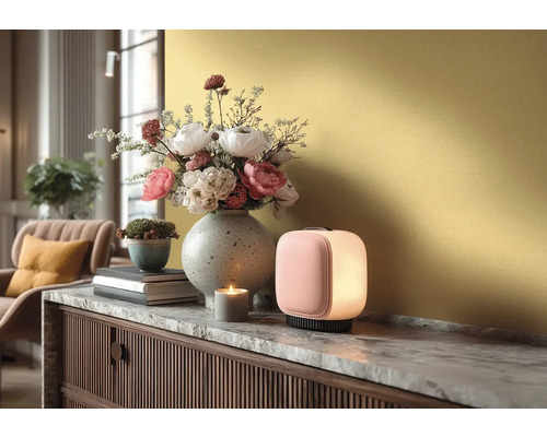 Moderne Tischleuchte auf einem Sideboard mit Marmorplatte, daneben eine Blumenvase, ein kleiner Pflanztopf und eine brennende Kerze.