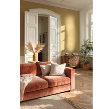 Helles Wohnzimmer mit ockerfarbener Wand, orangefarbenem Samtsofa, Fischgrätparkett, weißen Flügeltüren und Holzkommode.