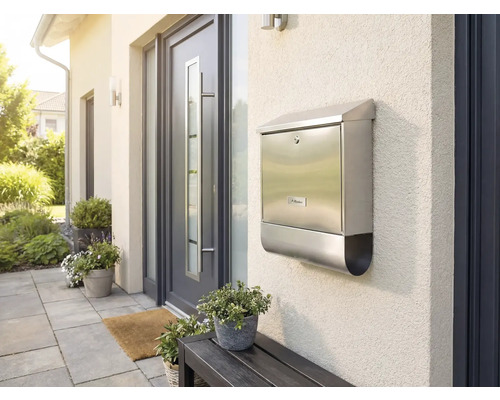 Boîte aux lettres en acier inoxydable sur un mur de maison à côté d'une porte d'entrée