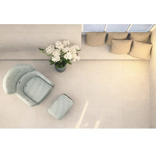 Espace lumineux avec fauteuil, repose-pieds, composition florale et canapé avec coussins, vu de dessus