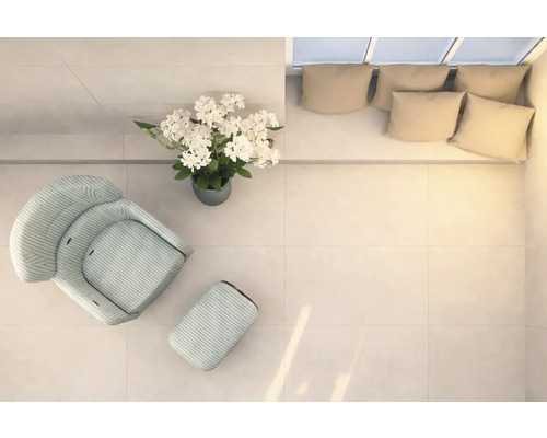 Espace lumineux avec fauteuil, repose-pieds, composition florale et canapé avec coussins, vu de dessus