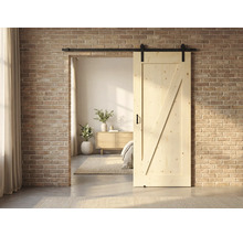 Porte coulissante en bois avec ferrures devant un mur de briques