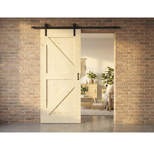 Porte coulissante en bois de style campagnard avec ferrures devant un mur de briques