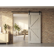 Porte coulissante en bois devant un mur en briques avec vue sur un salon lumineux