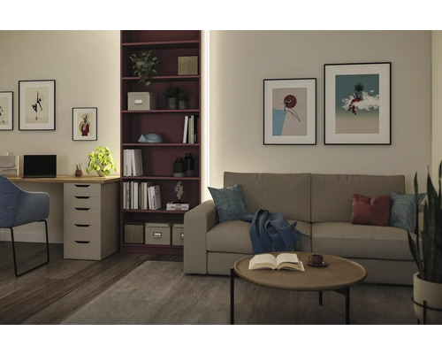 Heller, organisierter Raum mit grauem Stoffsofa, dunkelrotem Regal, Holzschreibtisch und gerahmter Wandkunst.