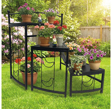 Mehrstöckiges Blumenregal aus Metall mit Pflanzen und Gartenzwergen im Garten.