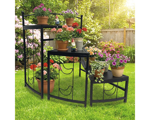 Mehrstöckiges Blumenregal aus Metall mit Pflanzen und Gartenzwergen im Garten.