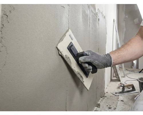 Handwerker glättet Wand mit einer Glättkelle und Spachtelmasse.